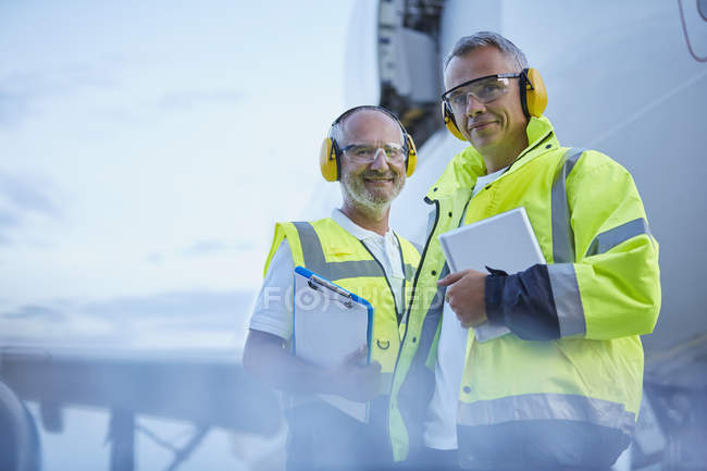 Portrait confident air traffic control ground crew workers with digital tablet near airplane on tarmac — Stock Photo