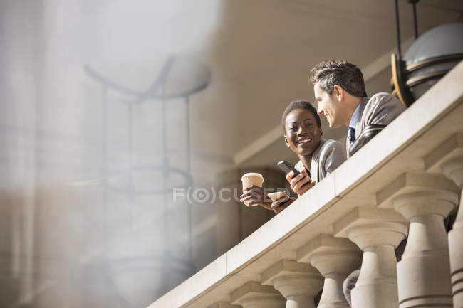 Corporate businessman and businesswoman drinking coffee at railing — Stock Photo