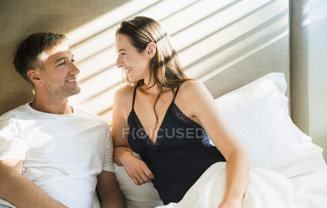 Sorrindo casal falando na cama juntos — Fotografia de Stock