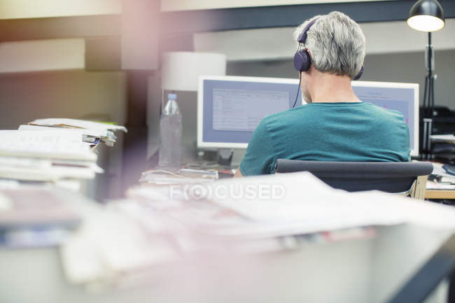 Homme d'affaires à l'écoute des écouteurs dans le bureau — Photo de stock