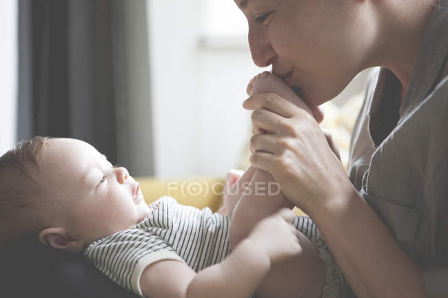 Мати тримає і цілує ноги маленької дитини — стокове фото