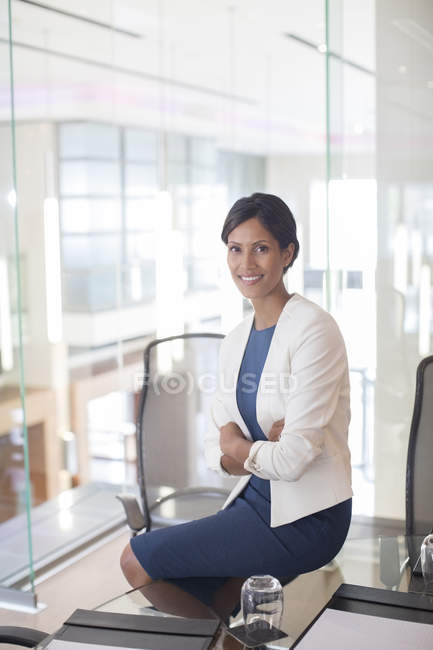 Retrato de bela mulher de negócios sorridente sentada à mesa de vidro na sala de conferências — Fotografia de Stock
