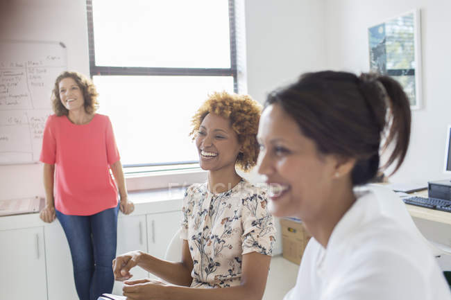 Три женщины смеются во время встречи в офисе — стоковое фото