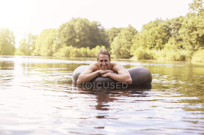 Чоловік плаває у внутрішній трубі в озері — стокове фото