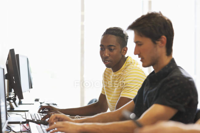 Side view of university students studying on computers in classroom — Stock Photo