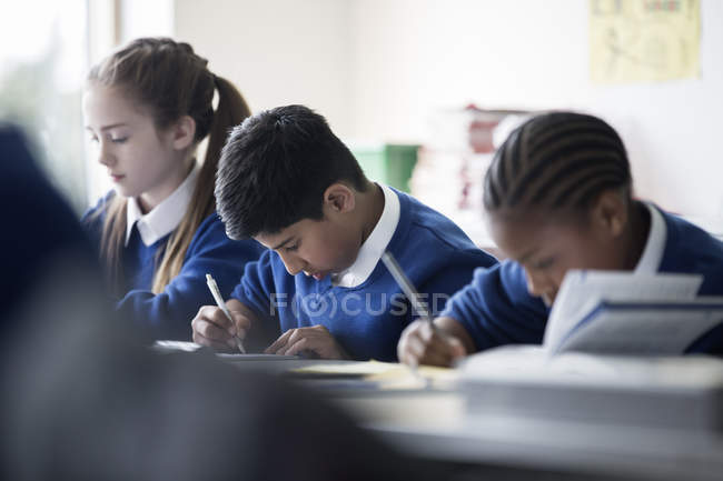 Elementary school children writing in classroom — Stock Photo