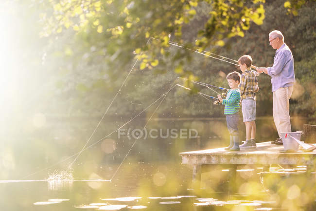 Grandfather and grandsons fishing at lake together — Stock Photo