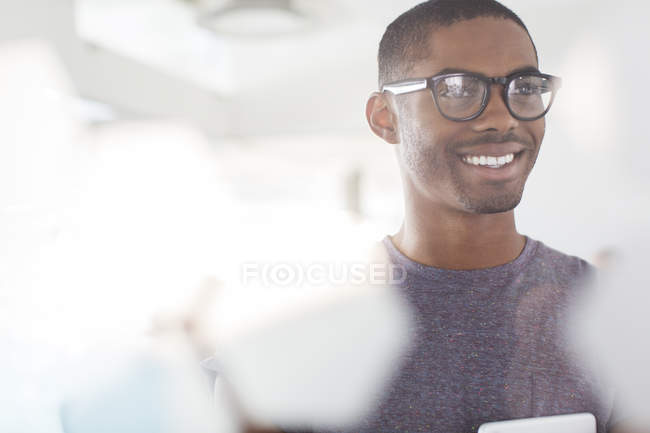 Portrait of young smiling businessman wearing glasses in office — Stock Photo