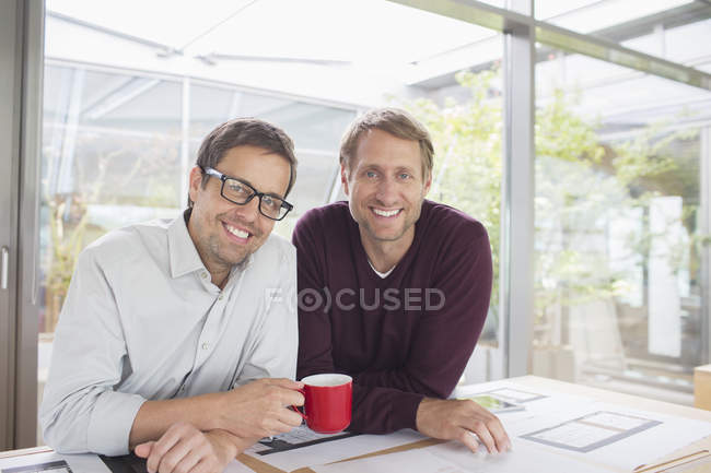 Empresarios sonriendo en escritorio de la oficina - foto de stock