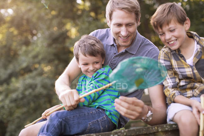 Padre e hijos pescando con red en muelle - foto de stock