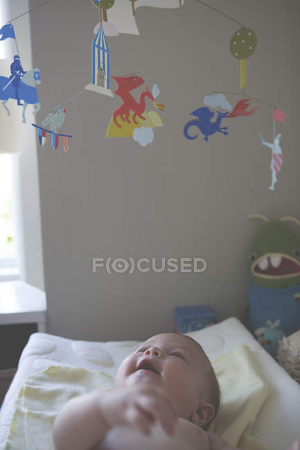 Little baby lying down and looking at colorful hanging mobile — Stock Photo