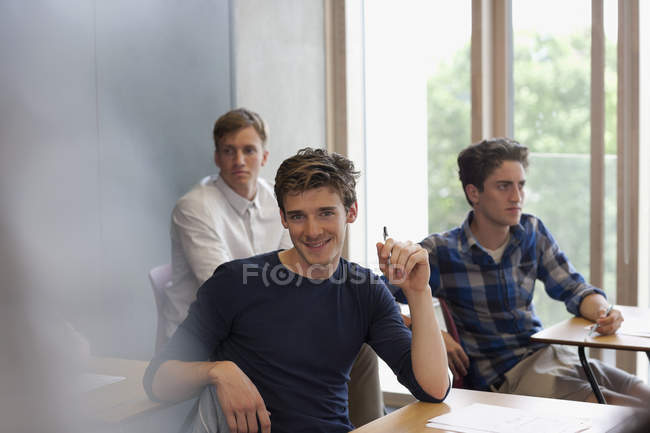 Retrato de estudante universitário sorridente sentado na mesa — Fotografia de Stock