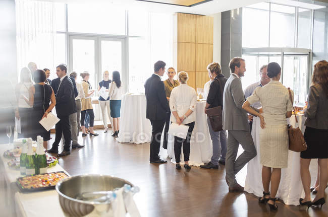 Group of conference participants standing in lobby of conference center, socializing during lunch break — Stock Photo