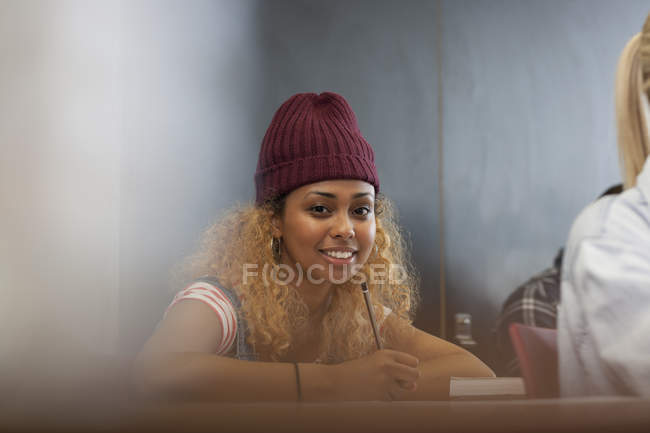 Портрет улыбающейся студентки университета, записывающей заметки в классе — стоковое фото