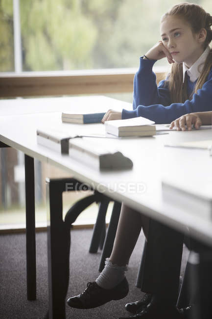 Élémentaire fille regardant ennuyé dans la salle de classe — Photo de stock