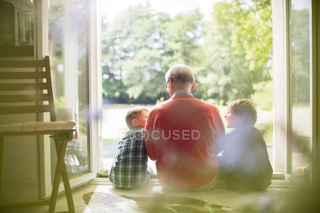 Дедушка и внуки сидят в дверях — стоковое фото