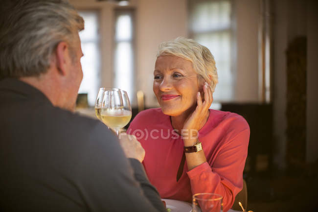 Couple plus âgé trinquant l'un à l'autre avec du vin blanc — Photo de stock