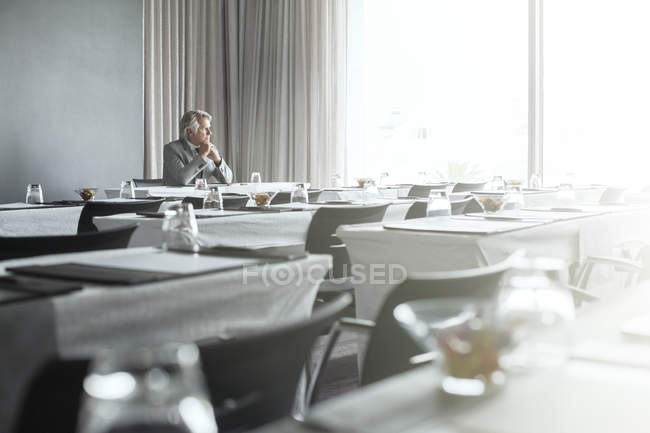 Mature businessman sitting in office restaurant with hands clasped — Stock Photo