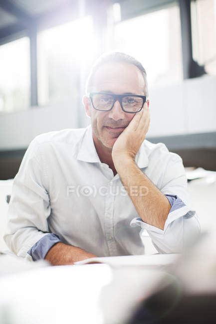 Lächelnder älterer Mann sitzt am Schreibtisch — Stockfoto