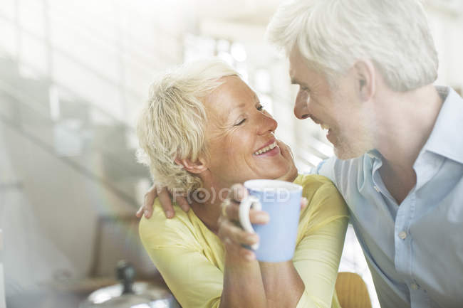 Älteres Paar umarmt sich mit Kaffeetasse — Stockfoto