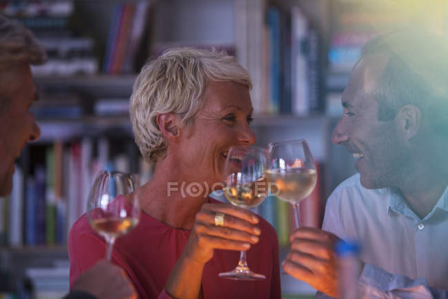 Amigos mayores brindando entre sí con vino blanco - foto de stock