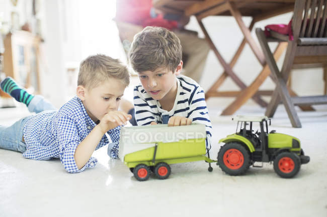 Brothers playing with toy tractor on floor — Stock Photo
