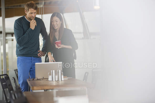 Business people using laptop in cafeteria — Stock Photo