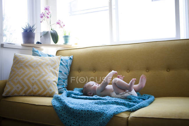 Bambino piccolo sdraiato su un panno blu con braccia e gambe sollevate — Foto stock
