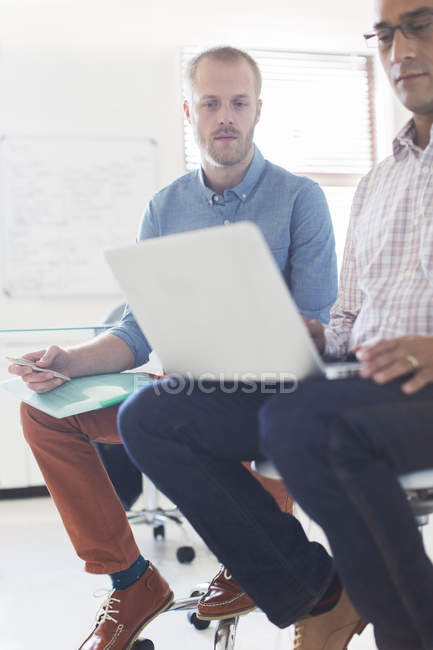 Два бізнесмени використовують ноутбук в сучасному офісі — стокове фото