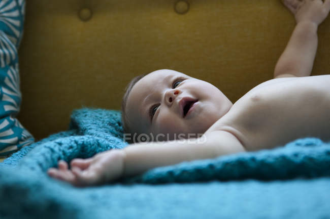 Ritratto di bambino sorridente sdraiato su un panno blu con le braccia tese — Foto stock