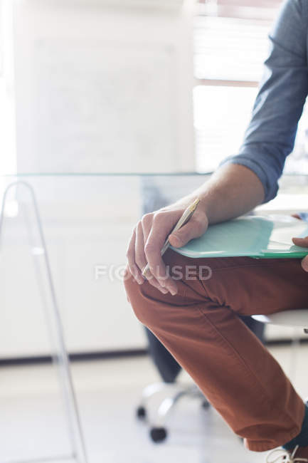 Perna e mão de homem segurando documentos e caneta — Fotografia de Stock