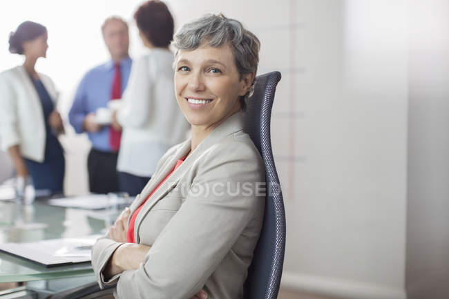 Porträt einer Geschäftsfrau, die mit verschränkten Armen im Konferenzraum sitzt — Stockfoto