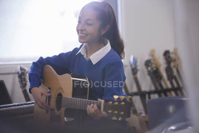 Улыбающаяся студентка, играющая на акустической гитаре — стоковое фото