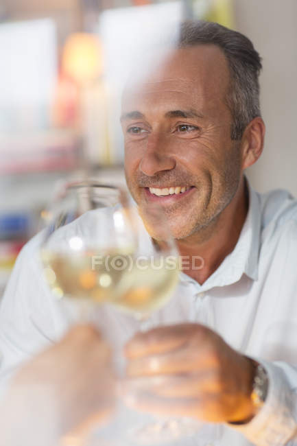 Hombre mayor sonriente tostando con vino blanco - foto de stock