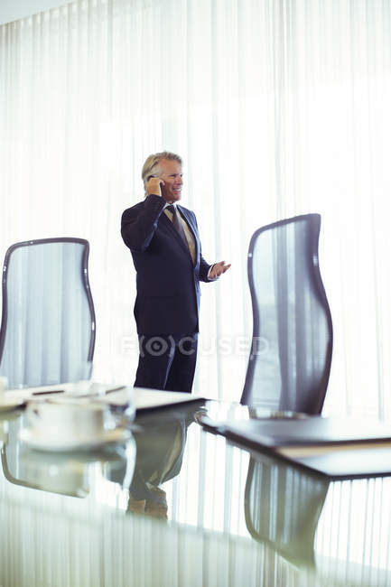 Uomo in piedi in sala conferenze a parlare sul suo cellulare — Foto stock