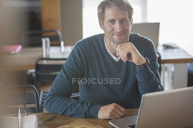 Empresário usando laptop na cafetaria — Fotografia de Stock