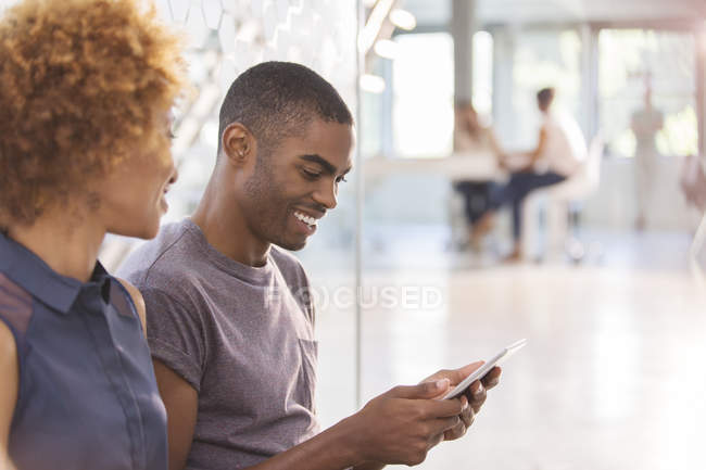 Mann und Frau mit digitalem Tablet im Büro, Kollegen im Hintergrund — Stockfoto