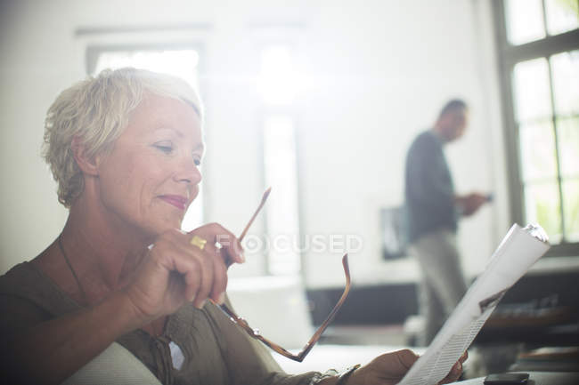 Businesswoman reading paperwork at home — Stock Photo