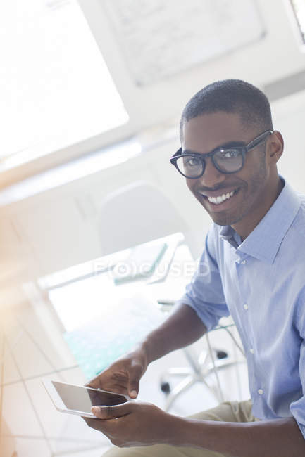 Retrato de jovem empresário sorrindo usando telefone inteligente no escritório — Fotografia de Stock