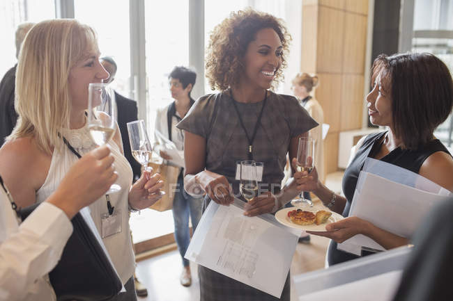 Mujeres de negocios sosteniendo flautas de champán y documentos durante el descanso de la reunión - foto de stock