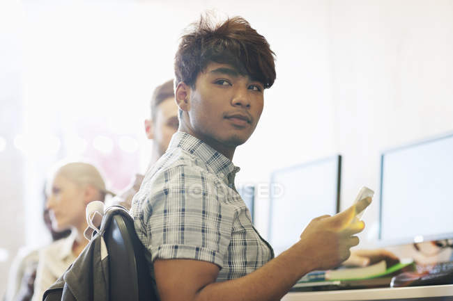Чоловік студент сидить за столом за допомогою мобільного телефону — стокове фото