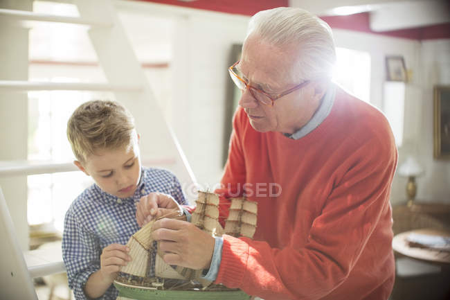 Дедушка и внук строят модель парусника — стоковое фото