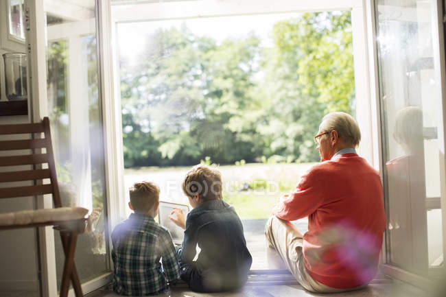 Abuelo y nietos relajándose en la puerta - foto de stock