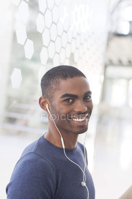Portrait of smiling young man with earphones in office — Stock Photo