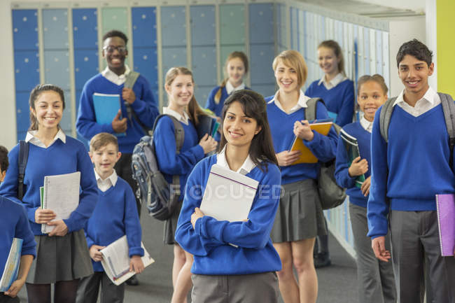 Групповой портрет школьников в школьной форме, стоящих в коридоре и улыбающихся — стоковое фото
