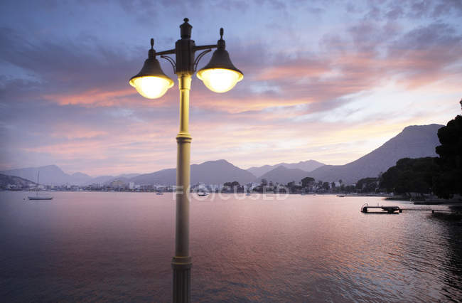 View of illuminated street light with bay and mountains in background — Stock Photo