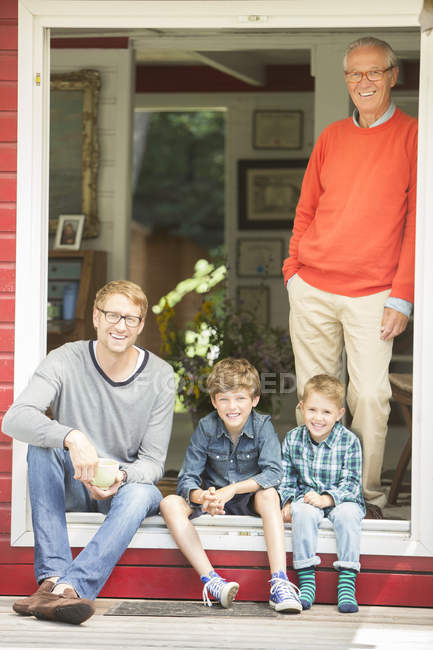 Братья улыбаются с отцом и дедушкой дома — стоковое фото