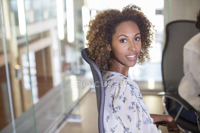 Porträt einer jungen Geschäftsfrau, die im Stuhl sitzt und in die Kamera blickt — Stockfoto
