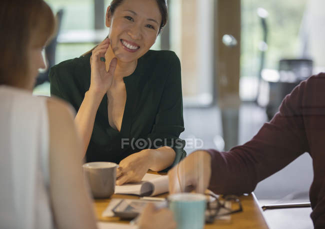 Empresarias sonriendo en reunión de oficina - foto de stock