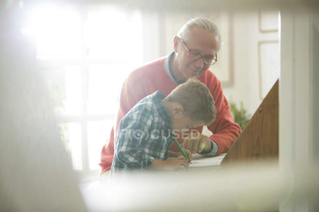 Caucasian grandfather and grandson writing at desk — Stock Photo
